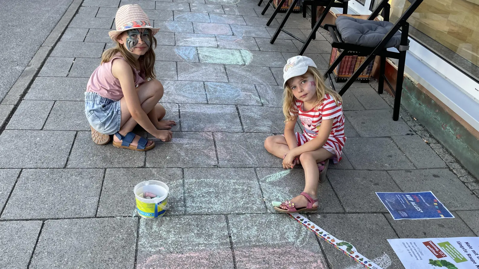 Auf dem Bürgersteig vor der Buchhandlung Lesezeichen malen Kinder die „kleine Raupe Nimmersatt” mit Kreide. Am Schluss war sie etwa 100 Schritte lang. (Foto: pst)