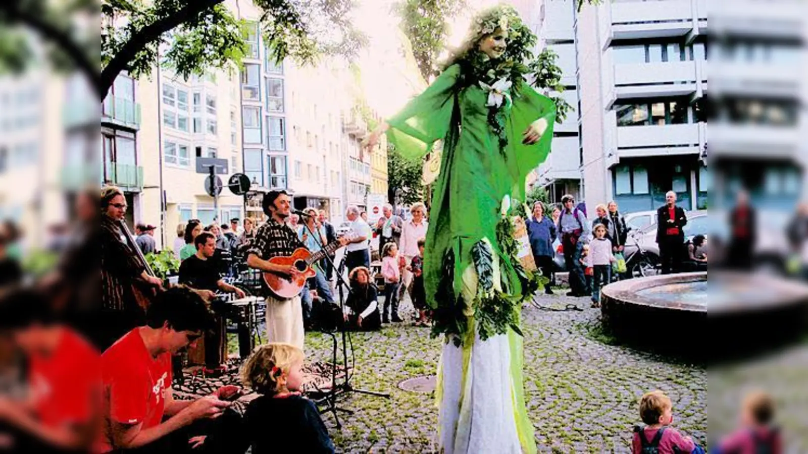 Die Stelzenläufer der Gruppe »Netzhaut« und Liedermacher Nathan untermalten die Wanderbaum­aktion am Artur-Kutscher-Platz. 	 (Foto: M. Drum)