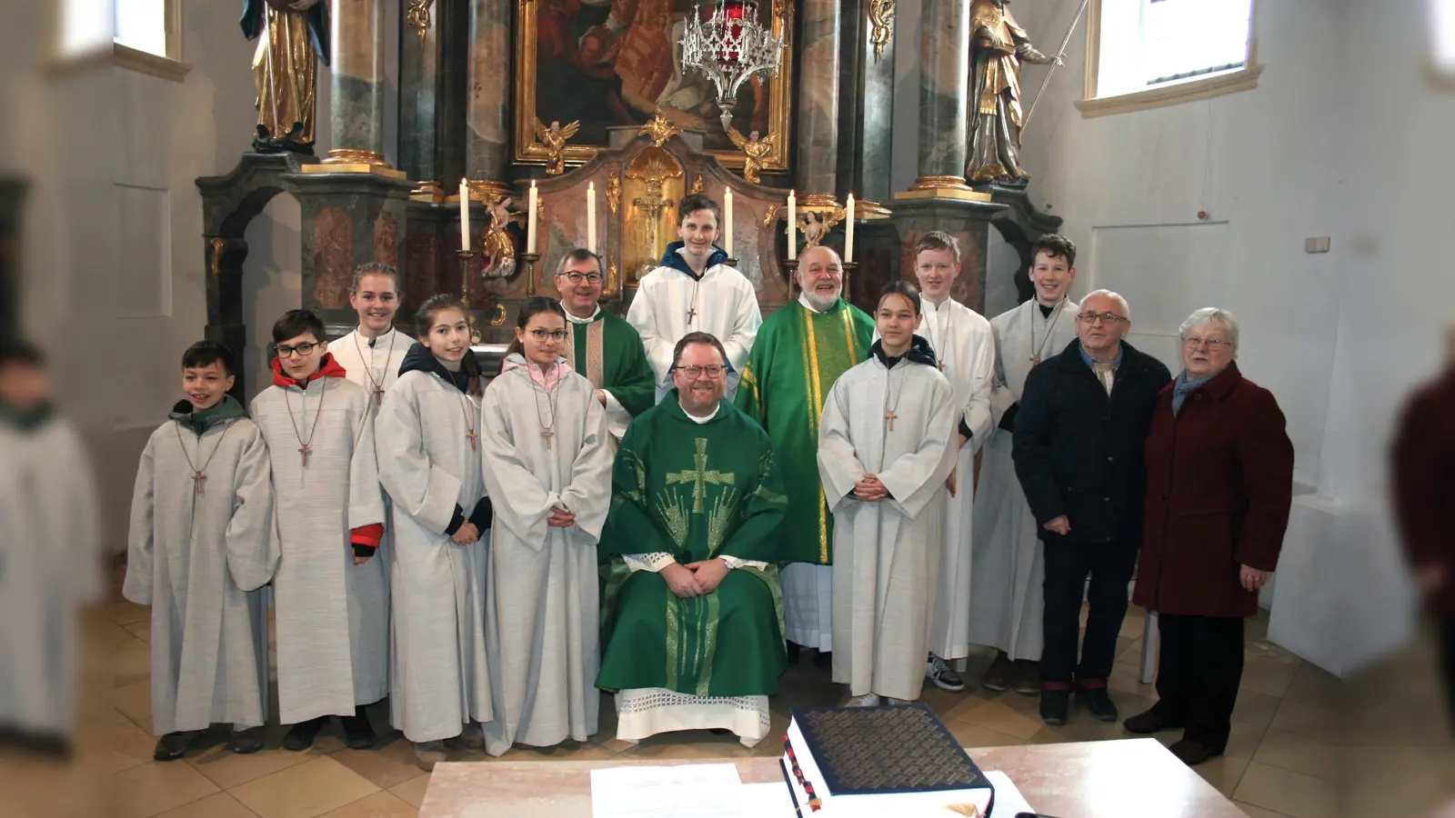 Gläubigen waren erfreut über den Pastoralbesuch von Dekan Pfarrer Björn Wagner (sitzend) in Landsham. Es freuten sich besonders über den Besuch und Zelebration des Gottesdienstes und für die vollbesetzte Kirche Pfarrer Werner Kienle (hi.li), Diakon Michael Ibler (hi.re), Kirchenverwalter Walter Ertl und Mesnerin Antonie Ertl (re.)sowie die neun Ministranten. (Foto: Georg Rittler)