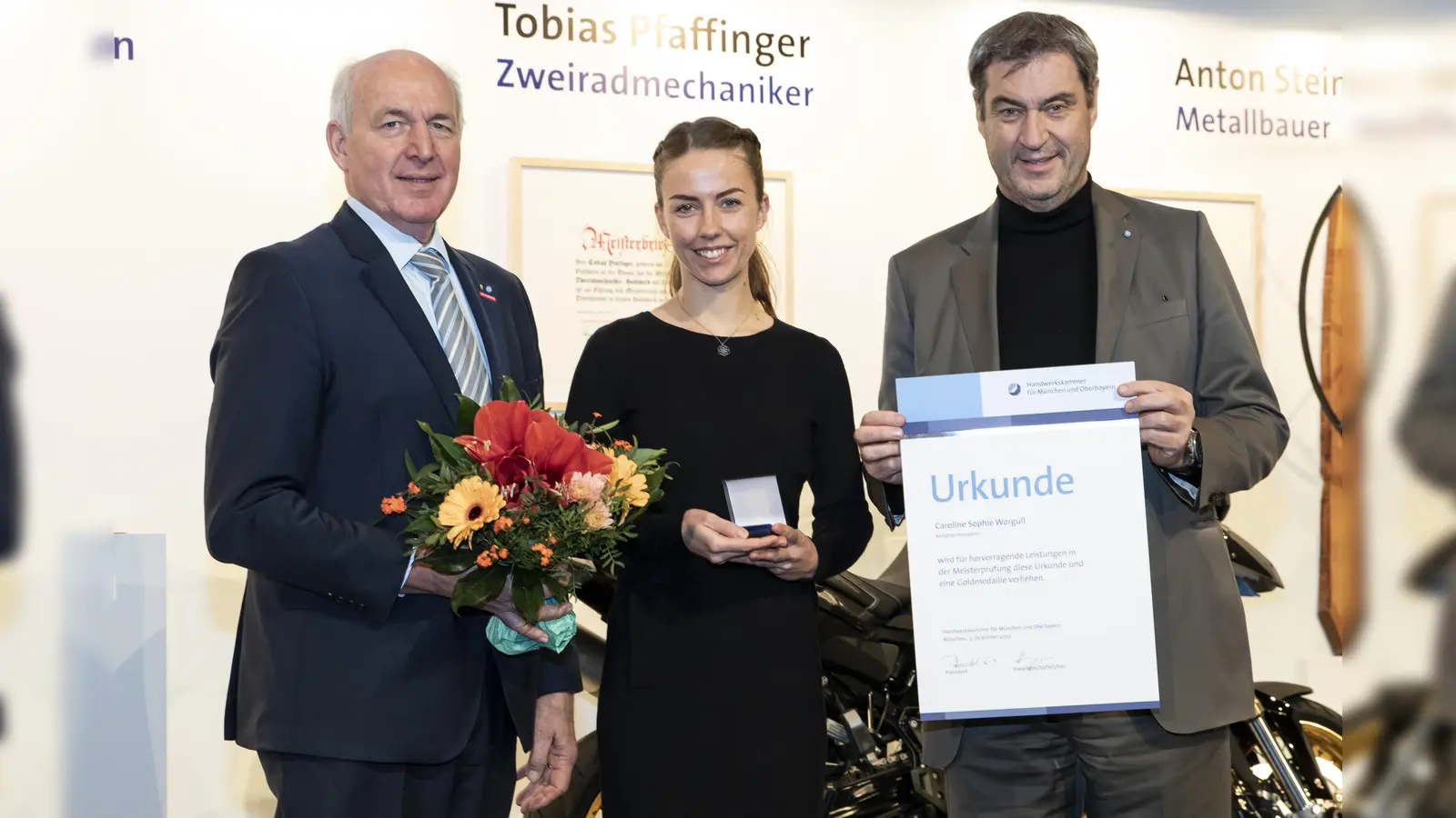 Handwerkskammerpräsident Franz Xaver Peteranderl und Ministerpräsident Markus Söder (rechts) gratulieren Jahresbestmeisterin Caroline Sophie Worgull.  (Foto: Michael Schuhmann)