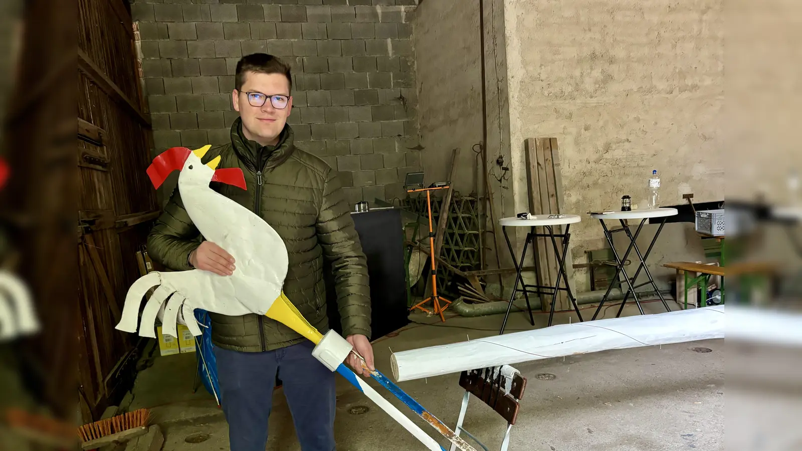 Der Hahn gehört zu den wertvollen dreidimensionalen Figuren am Obermenzinger Maibaum. Bis der montiert werden kann, muss noch die Raute am Baum gemalt werden. Vorstand Daniel Brems erklärte das Prozedere. (Foto: Ulrike Seiffert)