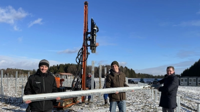 Zeigen einen der drei Meter langen Pfosten für die Freiflächen-Photovoltaikanlage, v.li.: Projektleiter Bernhard Kirchhofer, Planer Robert Sing und Bürgermeister Manfred Walter.  (Foto: pst)