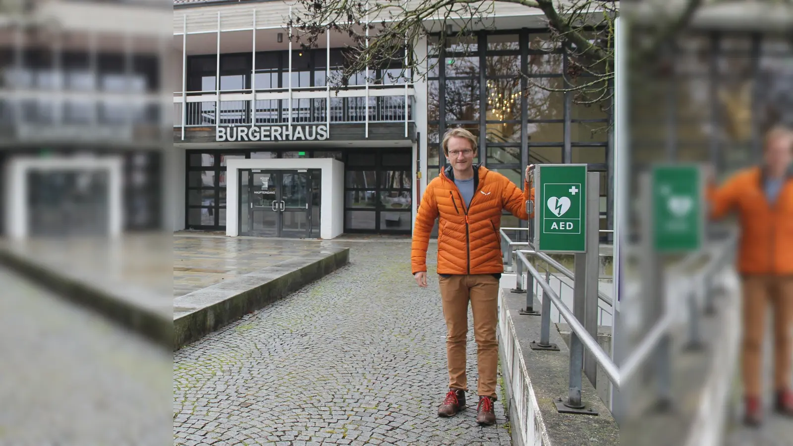 Bürgermeister Sebastian Thaler neben dem lebensrettenden Defibrillator, der vor dem Bürgerhaus, links neben den Infotafeln, steht.  (Foto: Gemeinde Eching)