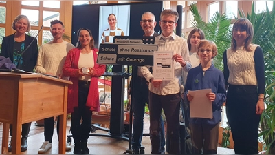 Freuen sich über die Plakette und Urkunde (von links): Schulleiterin Monika Aman, Regionalkoordinator Oberbayern Tobias Wolf, Lehrkraft Dr. Anne Stempel, Schülervater Ulrich Zehfuß, SMV-Mitglied Sebastian Heinke, SMV-Mitglied Leandra Schalm, SMV-Mitglied Leonard Pröll, Lehrkraft Tine Hohmann; im Hintergrund zu sehen Patin Sydney Lohmann. (Foto: Elisabeth Hiemer)