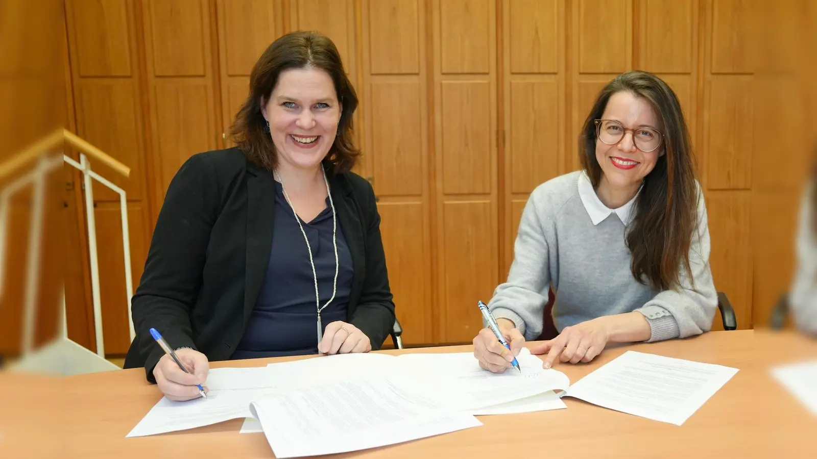 Die Aufsichtsratsvorsitzende der Münchner Volkshochschule, Verena Dietl, und Marina May (r.) unterzeichnen Mays Vertrag als neue Programmdirektorin der MVHS.  (Foto: LHM)