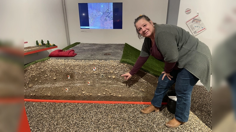 Annette Reindel zeigt beim Querschnitt der Römerstraße im Museum in welcher Erdschicht die dritte Reparatur erfolgt ist.  (Foto: Patrizia Steipe)