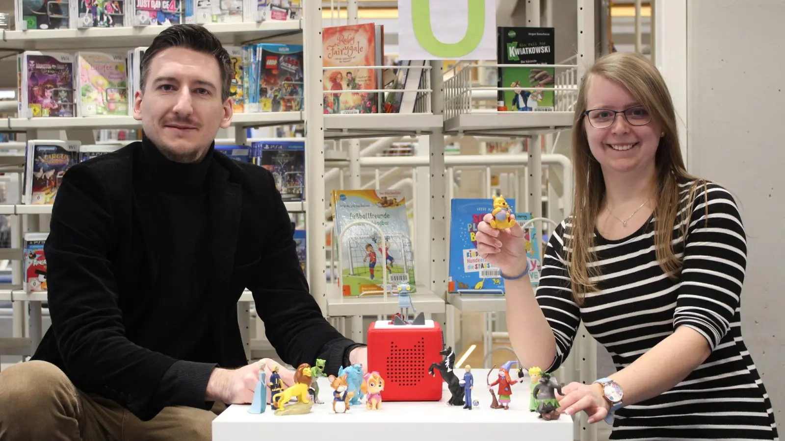 Büchereileiter Jan Marberg und Mitarbeiterin Anita Stirnadel präsentieren einige der Tonie-Hörfiguren, die sich einer hohen Nachfrage erfreuen. (Foto: Stadtbücherei Weilheim)