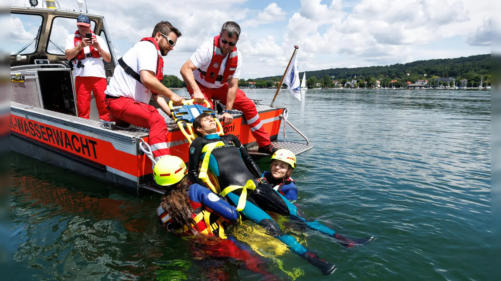 Das Team der Wasserwacht Herrsching zeigte Katharina Schulze (im Wasser rechts) wie es sich anfühlt bei der Wasserwacht zu sein. Benjamin Taitsch (zweiter von links) und Marcus Röttel (rechts) unterstützen den Schnupper-Rettungseinsatz der Politikerin. (Foto: Matthias Balk (Fotografie) / www.matthiasbalk.com)