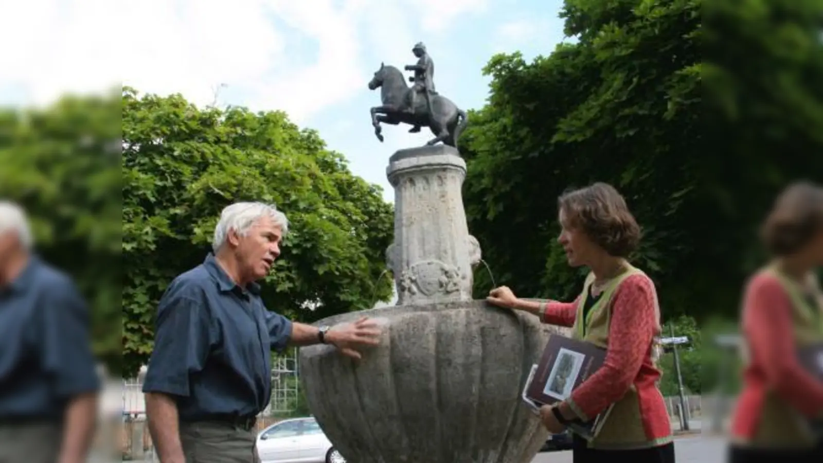 Simon Erber und Gudrun Koppers-Weck (v.l.) im Gespräch am Brunnen auf dem  Wensauerplatz. Seit über zwanzig Jahren steht eine Nachempfindung er ursprünglichen Bismarck-Figur auf dem Brunnen. Nun soll das Original zurück auf seinen angestammten Platz. (Foto: US)