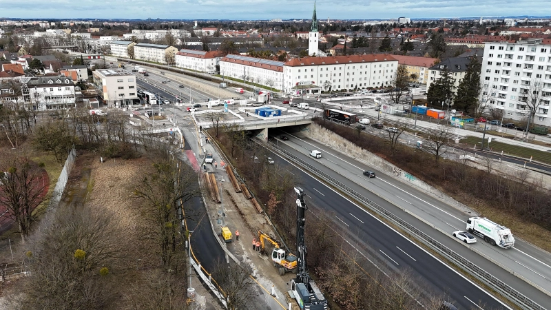 Blick auf die Brücke, auf der die Fürstenrieder Straße die A 96 quert. Im Vordergrund die Baustelleneinrichtung für den „Bypass”; links daneben das Gelände der früheren Landesgehörlosenschule. Der Kirchturm hinten rechts ist der von Namen Jesu. (Foto: SWM/MVG)