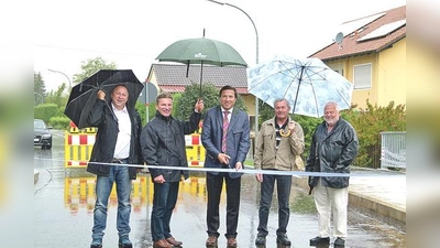 Mit einem Schnitt durch das weiß-blaue Band gab Bürgermeister Max Gotz (Mitte) bei strömendem Regen die Semptbrücke in Eichenkofen wieder für den Verkehr frei. 	 (Foto: bb)