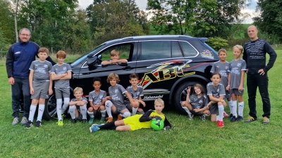 Stolz präsentieren die Spielerinnen und Spieler mit Trainer Mathias Timm (rechts) die neuen Trikots, die ihnen von Michael Gilg (links) von der ABC-Fahrschule überreicht worden sind.  (Foto: SC Huglfing)