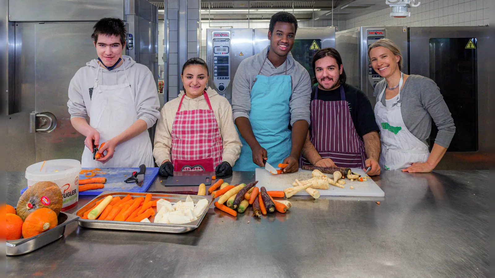 Gemeinsam kochen und anderen etwas Gutes tun (von links): Tobias, Adriana, Mohamed und Guiseppe hatten mit ihrer Lehrerin Annette Fendler großen Spaß beim Gemüseschneiden in der Community Kitchen. (Foto: Augustinum/Christian Topp)