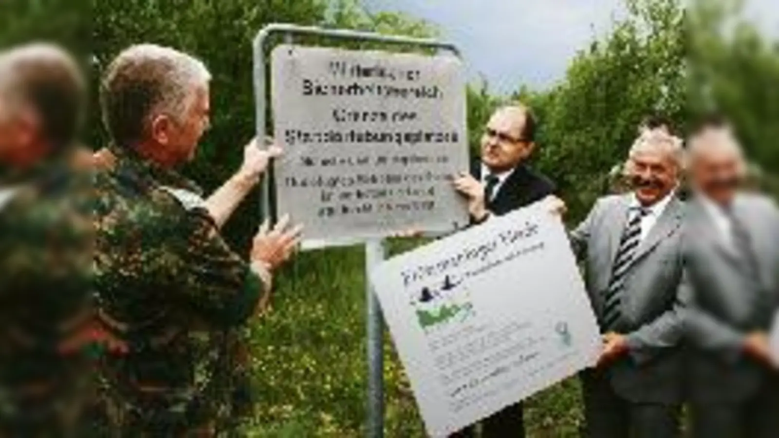 Zapfenstreich  während Oberst Norbert Reinelt und Staatssekretär Christian Schmidt mit der Demontage des alten Warnhinweises beschäftigt sind, präsentiert Bürgermeister Rolf Zeitler stolz das neue Schild.  (Foto: wei)