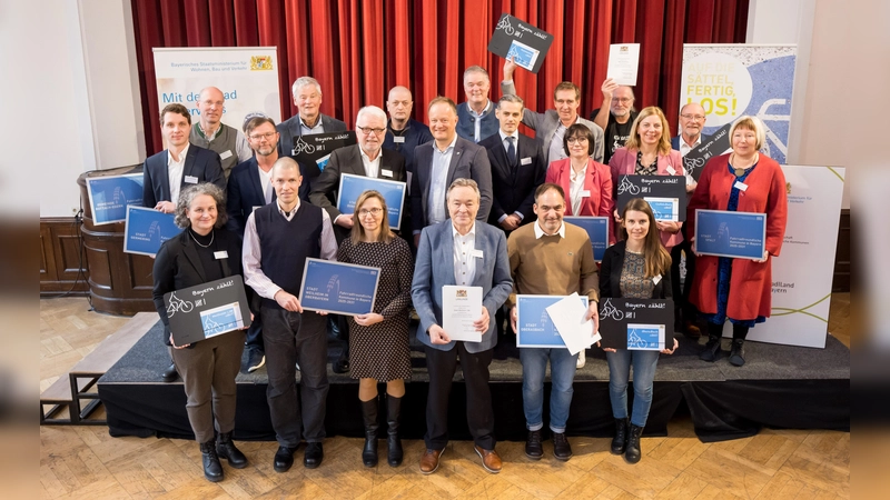 Die Delegationen der zertifizierten und rezertifizierten Mitgliedskommunen mit dem Vorsitzenden der AGFK, Landrat Robert Niedergesäß, und Christian Heck, Leiter des Referats Radverkehr im StMB (Mitte). (Foto: AGFK Bayern/Tobias Hase)