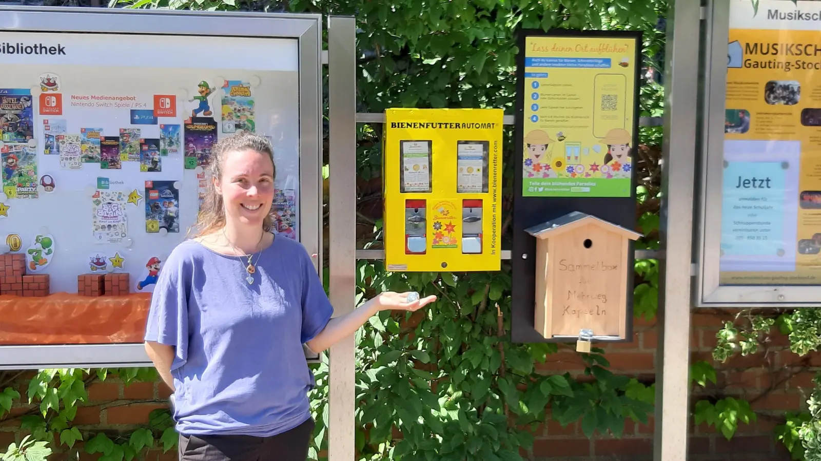 Michaela Thiel, die Naturschutzbeauftragte der Gemeinde Gauting, präsentiert den ersten Gautinger Bienenfutterautomaten am Rathaus.  (Foto: Gemeinde Gauting)