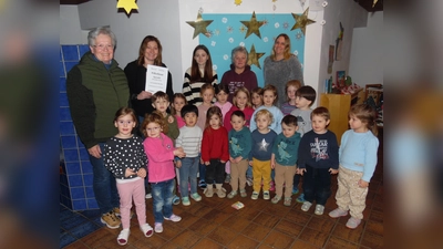 Anni Wachinger (li) überreicht der Leiterin des Kindergarten St. Barbara Bettina Huber und ihrem Team den Spendenscheck. Freudig und überrascht aufgenommen wurde es auch von einer Schar Kinder die sich gerne dem Fotografen stellten. (Foto: Georg Rittler)