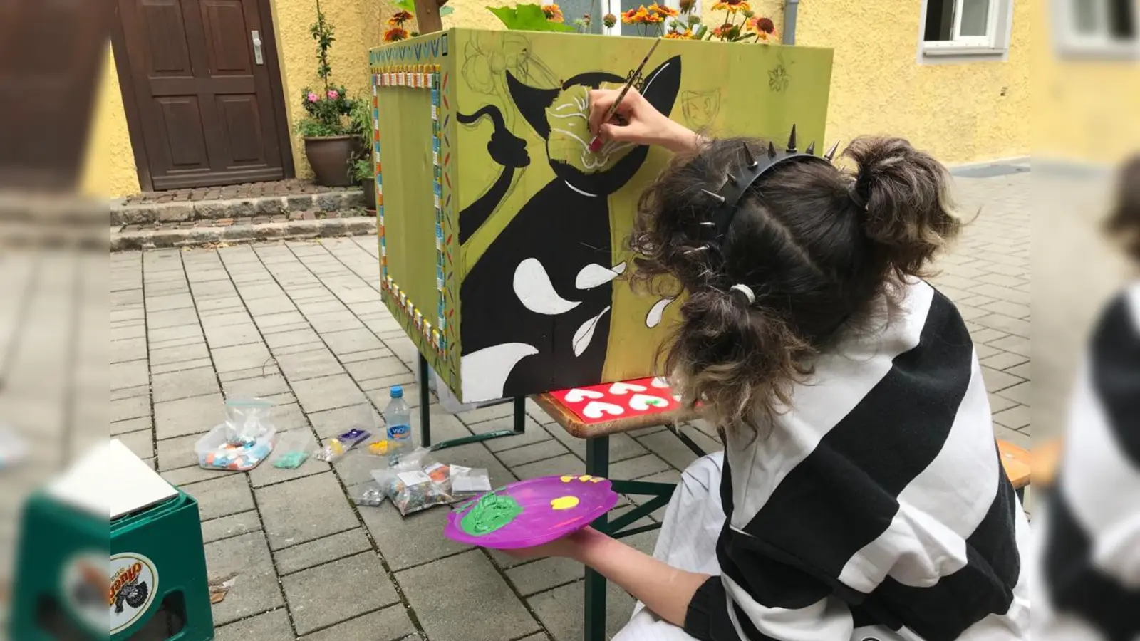 Mit selbst bemalten, bunten Pflanztrögen trägt „Artists for Kids“ zur Gestaltung der Aktionsfläche in der Schießstättstraße, dem Sommerexperiment zum „Westend Kietz“ bei. Im Bild: Dilara (20). (Foto: Artists for Kids)