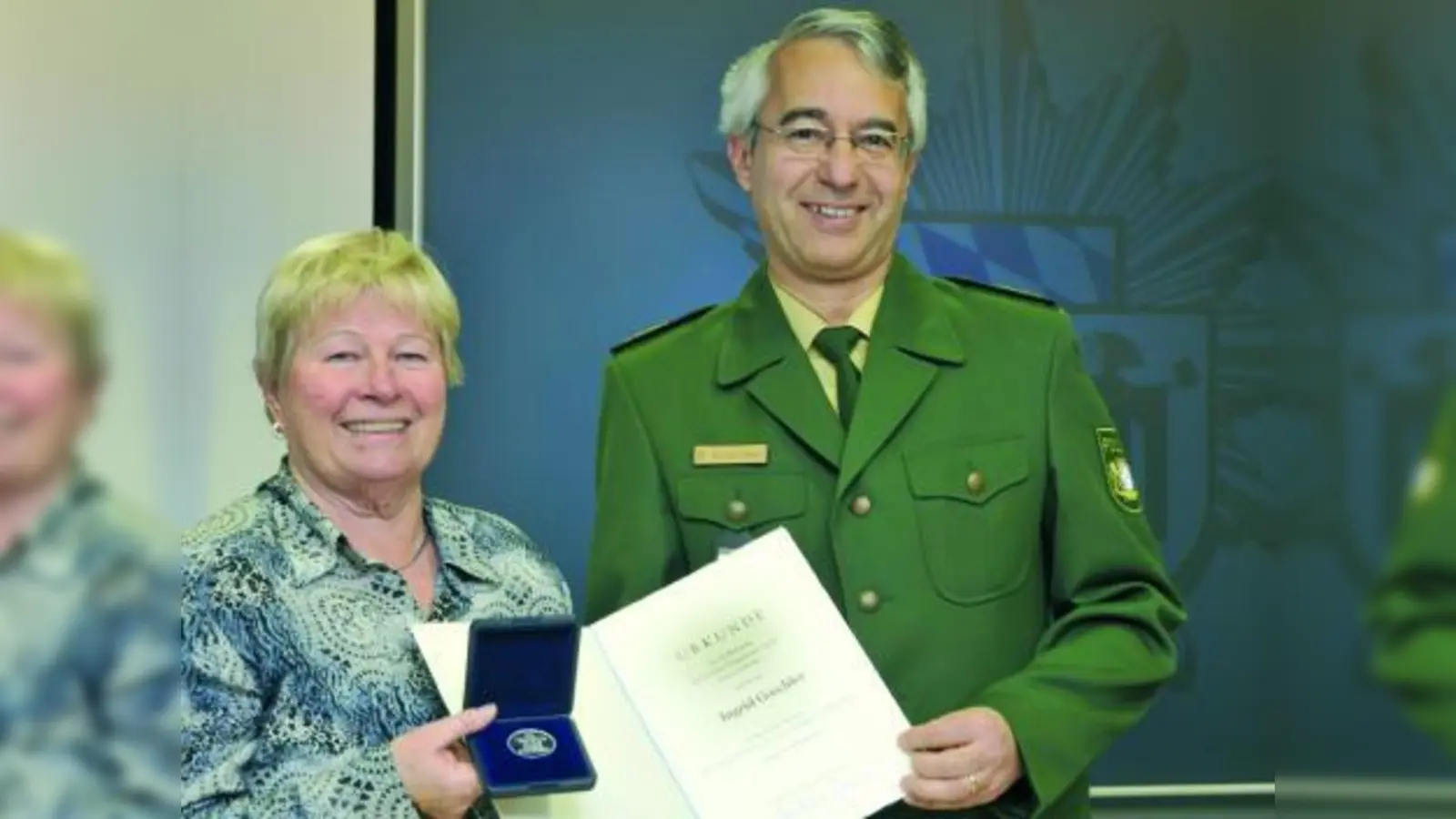 Polizeipräsident Wilhelm Schmidbauer überreicht der mutigen Rentnerin Ingrid G. die Verdienstmedaille mit dazugehöriger Urkunde. Der Kontakt zwischen Opfer und Zeugin hält bis heute an: „Wir telefonieren auf jeden Fall einmal pro Woche und sehen uns regelmäßig”, so Ingrid G. (Foto: Polizei)