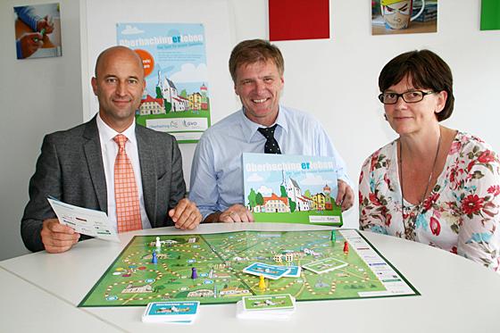 Christoph Müller-Brandt, Bürgermeister Stefan Schelle und Gabriele Greenlee (v. l.) präsentieren das 1. Oberhaching-Spiel.  	Foto: hol